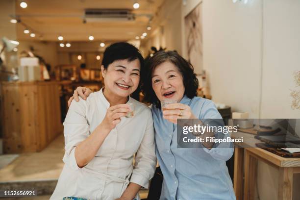 two mature ladies drinking tea together - taipei tea stock pictures, royalty-free photos & images