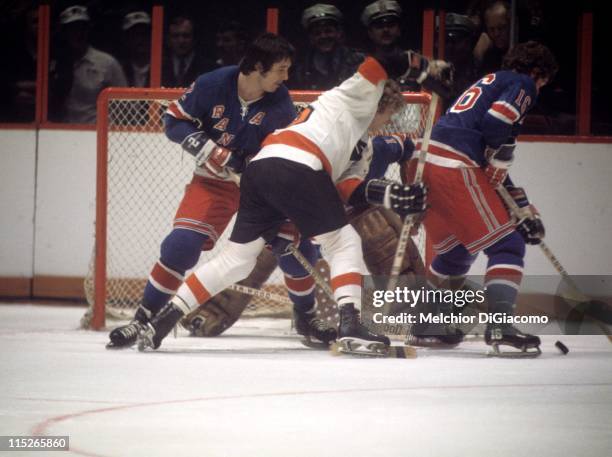 Rod Seiling of the New York Rangers skates with the puck as Bobby Clarke of the Philadelphia Flyers tries to score while being defended by Brad Park...