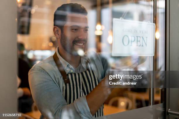 kellner arbeitet in einem restaurant und setzt ein offenes schild an die tür - open sign on door stock-fotos und bilder