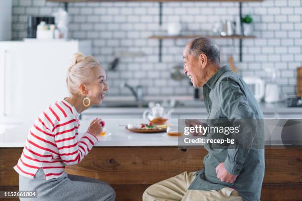 senior couple having tea in kitchen - married imagens e fotografias de stock