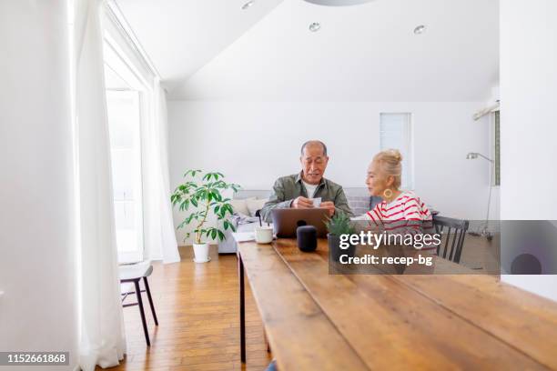 happy senior par som använder laptop hemma - japanese senior couple bildbanksfoton och bilder