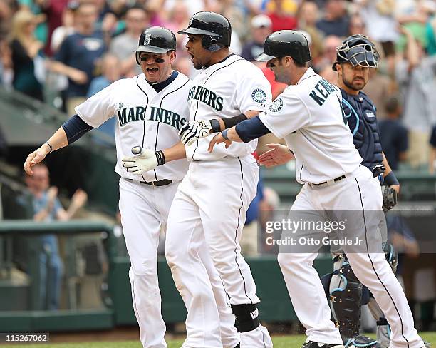 Miguel Olivo of the Seattle Mariners is congratulated by Jack Cust and Adam Kennedy after hitting a three run homer in the eighth inning to take a...