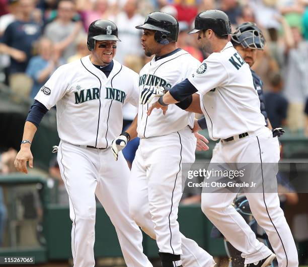 Miguel Olivo of the Seattle Mariners is congratulated by Jack Cust and Adam Kennedy after hitting a three run homer in the eighth inning to take a...