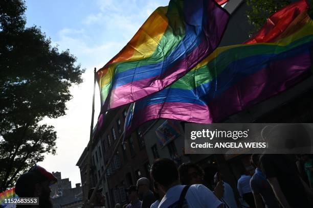 Person holds rainbow flags outside the Stonewall Inn during a rally to mark the 50th anniversary of the Stonewall Riots in New York, June 28, 2019. -...