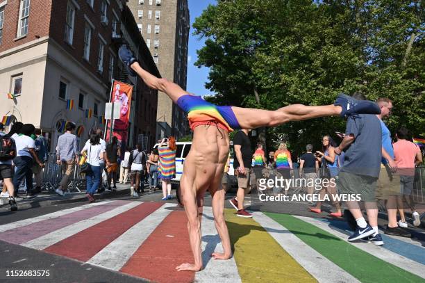Man does a cartwheel in the street as people gather outside the Stonewall Inn during a rally to mark the 50th anniversary of the Stonewall Riots in...