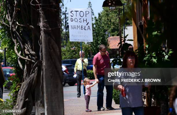 Protestor holds a sign while keeping his distance from the bookstore where drag queens read to adults and children during Drag Queen Story Hour at...