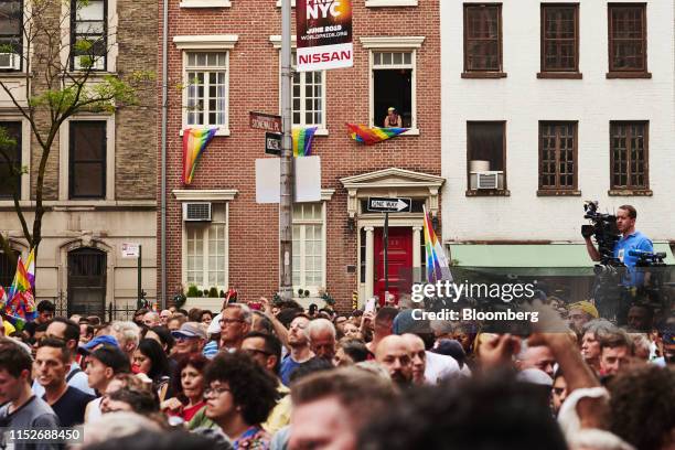 Resident watches from a window as attendees gather during a Stonewall Inn 50th anniversary commemoration rally in New York, U.S., on Friday, June 28,...