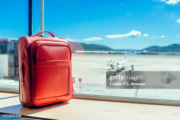 suitcase in airport with airplane in the background - bagagli foto e immagini stock