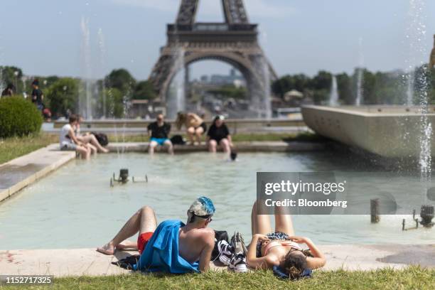 People sunbathe at the Trocadero esplanade fountain near the Eiffel Tower in Paris, France, on Friday, June 28, 2019. Europeans fought to stay cool...