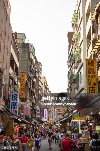 people walking down tamsui old street day market in taipei, taiwan - tamsui-old-street stock pictures, royalty-free photos & images