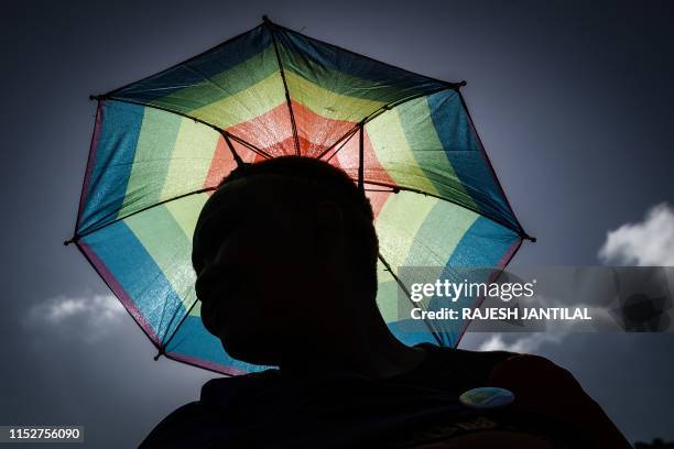 Member of the South African Lesbian, Gay, Bisexual and Transgender and Intersex community holds an umbrella in the rainbow flag colours takes part in...