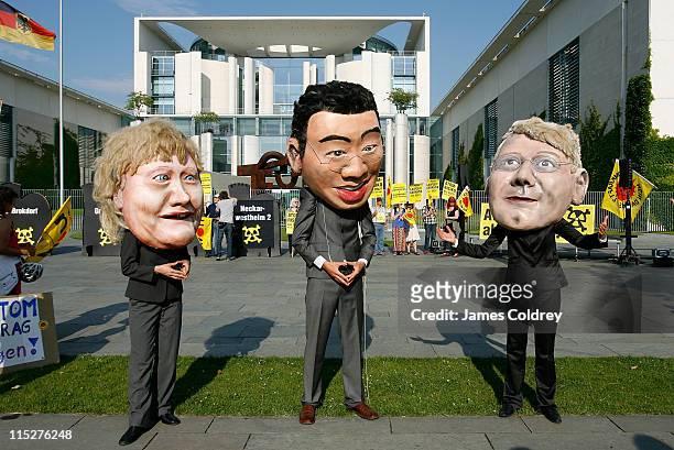 Anti-nuclear protesters display effergies of Angela Merkel, Philipp Roesler and Norbert Roettgen outside the Chancellery shortly before the weekly...