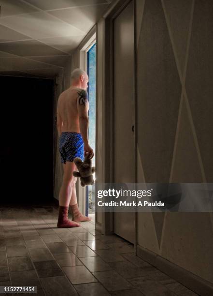 man going into illuminated room holding a teddy bear - lost sock stock pictures, royalty-free photos & images