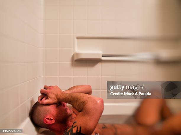 man laying in white bathtub with hands on head - sighing stock pictures, royalty-free photos & images