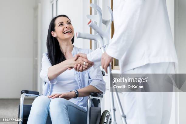 senior doctor helpt bij de vrouw met revalidatie - crutches stockfoto's en -beelden