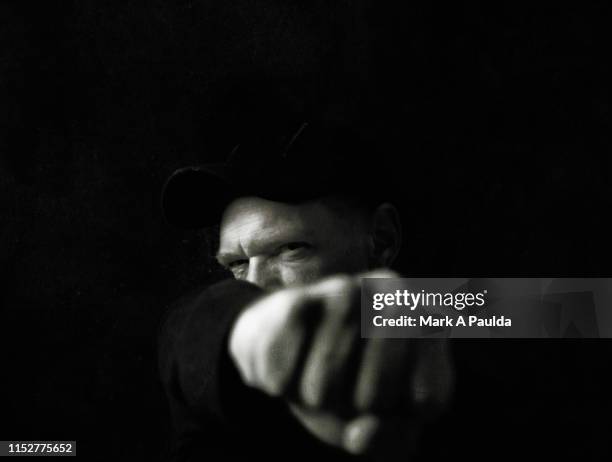 man punching his fist into the foreground - ominous man stock pictures, royalty-free photos & images