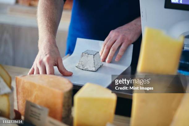 cheeseseller wrapping up goats cheese - cheese shop stock-fotos und bilder