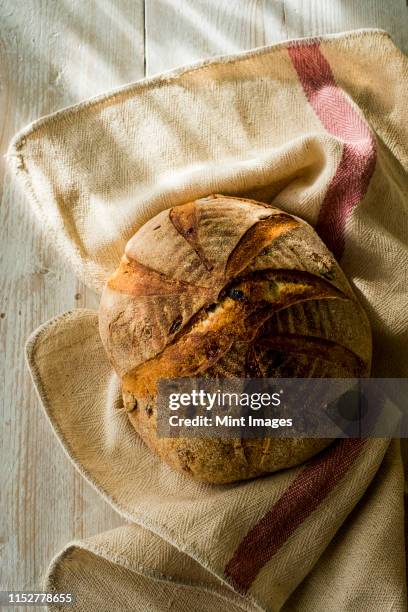 high angle close up of a freshly baked round loaf of bread on tea towel. - dish towel stock pictures, royalty-free photos & images