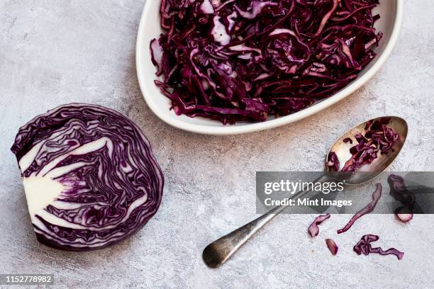 a dish of cooked red cabbage and half a raw cabbage. - rotkohl stock-fotos und bilder
