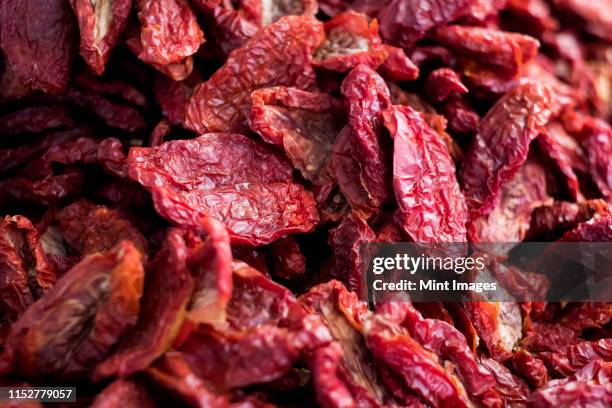 high angle close up of dried red tomatoes at a market stall. - sonnengetrocknete tomate stock-fotos und bilder