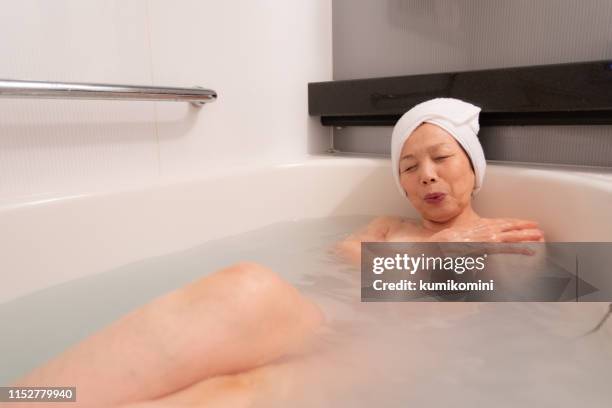 senior woman relaxing in bath - japanese women bath stock pictures, royalty-free photos & images