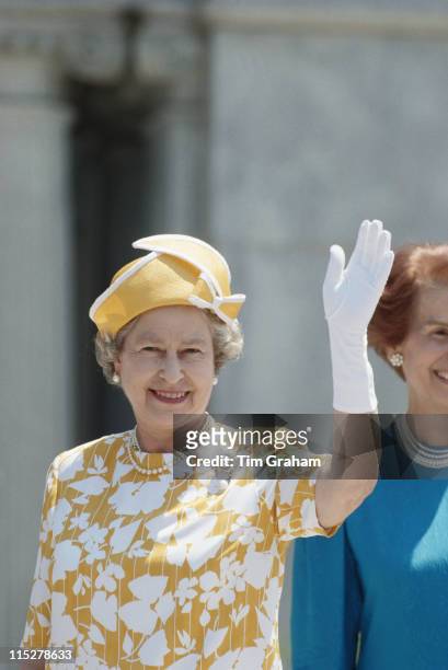 Queen Elizabeth II, wearing a yellow hat, a white and yellow dress and white gloves, waving during an official visit to Washington, DC, USA, 15 May...