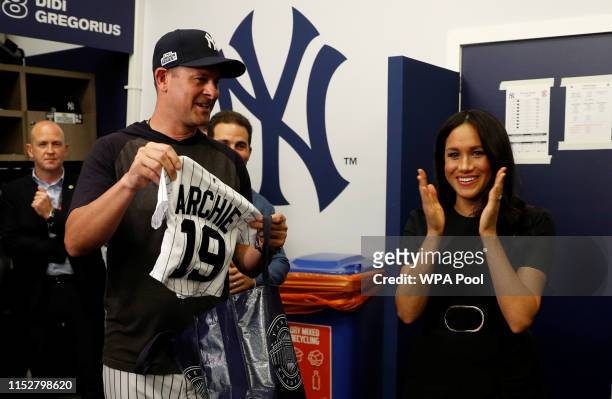 Manager Aaron Boone of the New York Yankees presents a gift for Archie to Prince Harry, Duke of Sussex and Meghan, Duchess of Sussex before their...