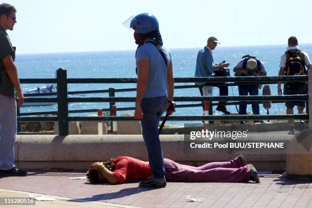 Police officer in plain clothes stands over a demonstrator on the ground during protests against the 27th Group of Eight Summit in July, 2001 in...