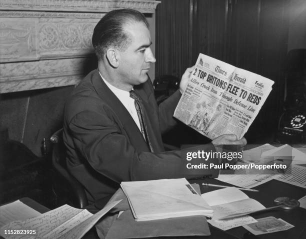 Senator from Wisconsin, Joseph McCarthy holding a copy of the Washington Times-Herald newspaper with a headline referring to the defection of British...