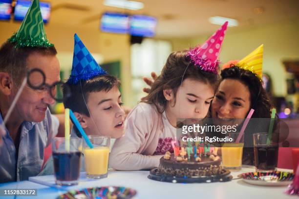 family helping girl to blow birthday candles - bowling party stock pictures, royalty-free photos & images