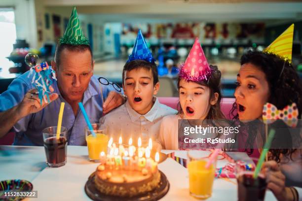 parents and children blowing birthday candles - bowling party stock pictures, royalty-free photos & images