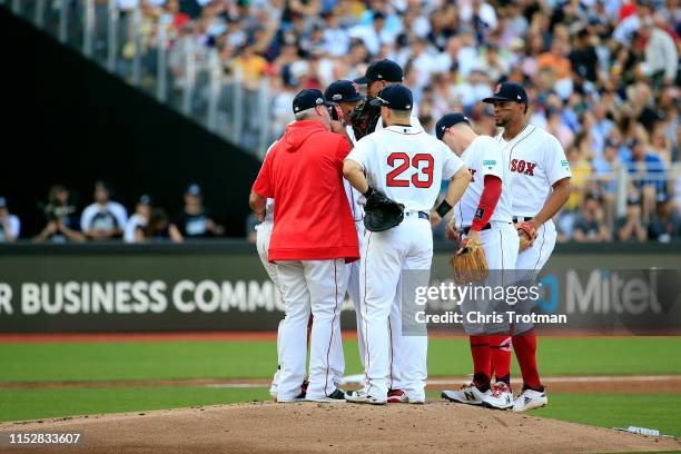 Rich Porcello of the Boston Red Sox is visited on the mound in the first inning of game one of the London Series between the New York Yankees and the...