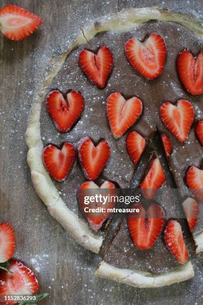 image of homemade chocolate pizza with strawberries and icing sugar, baked pizza crust filled with hazelnut chocolate spread and topped with romantic red love heart shape slices of strawberries / strawberries fruit, ready to be sliced and eaten as pudding - heart shape pizza stock pictures, royalty-free photos & images