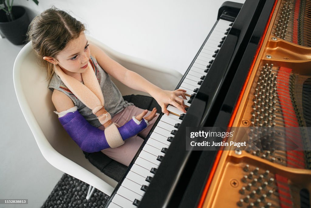 Young girl with broken arm playing piano