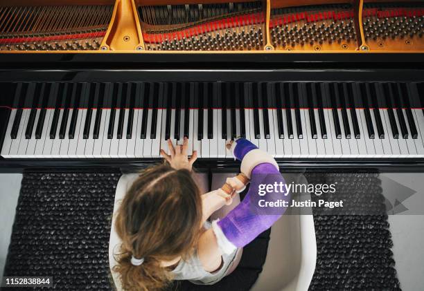 young girl with broken arm playing piano - kind mit armschlinge stock-fotos und bilder