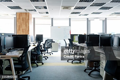 Sillas vacías y PCs de sobremesa en los escritorios de la oficina Sillas vacías y PCs de sobremesa en los escritorios de la oficina