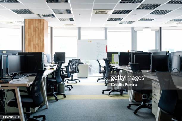 sillas vacías y pcs de sobremesa en los escritorios de la oficina - empty office fotografías e imágenes de stock