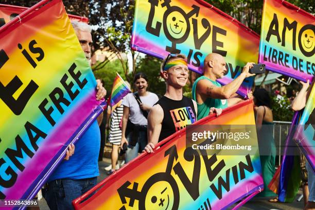 Attendees hold signs during a Stonewall Inn 50th anniversary commemoration rally in New York, U.S., on Friday, June 28, 2019. Fifty years ago today,...