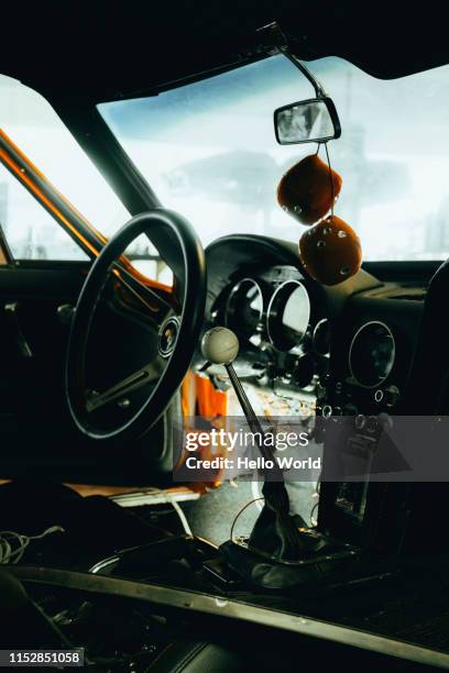 interior of a vintage car with dice hanging from rear-view mirror - auto zerlegt stock-fotos und bilder