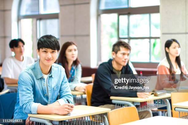 portrait of confident male student sitting in the classroom - ambassador stock pictures, royalty-free photos & images