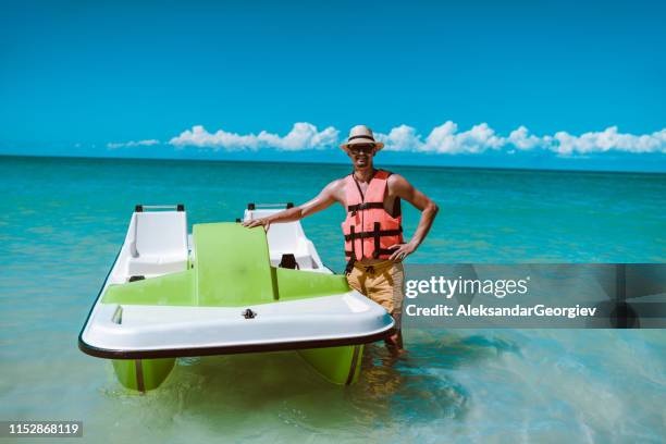 mâle heureux présentant sa méthode préférée de amusement de plage - pedal boat photos et images de collection