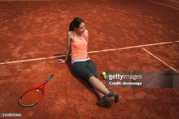 young woman resting on the clay court after a tennis training class - clay court stock pictures, royalty-free photos & images
