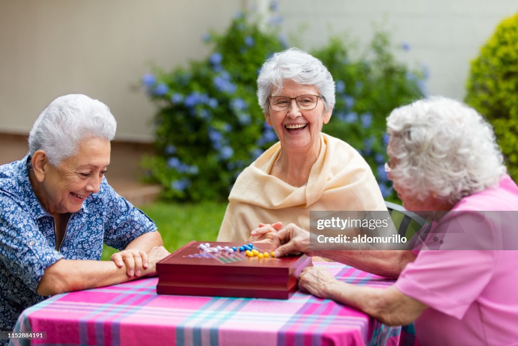 Cheerful elderly women playing boardgame outside