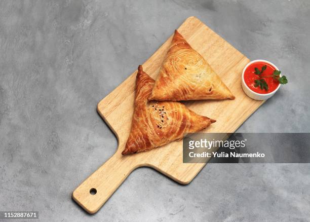 cutting board with delicious meat samosas and red sauce on gray background - brick photos et images de collection