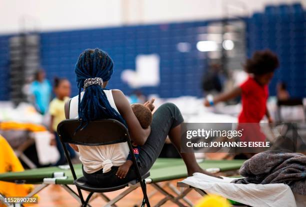 Migrant holds her baby at The Expo, a sports complex converted into an emergency shelter, on June 25, 2019 in Portland, Maine. - Converging from far...