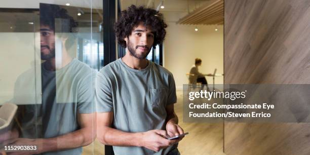 creative businessman using cell phone in modern office - capelli neri foto e immagini stock