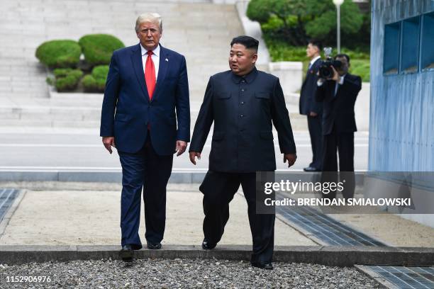 North Korea's leader Kim Jong Un and US President Donald Trump cross south of the Military Demarcation Line that divides North and South Korea, after...