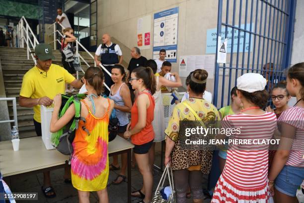 Security personnel and municipal police officers check the bags of people entering the Jean Bron swimming pool in Grenoble, central-eastern France,...