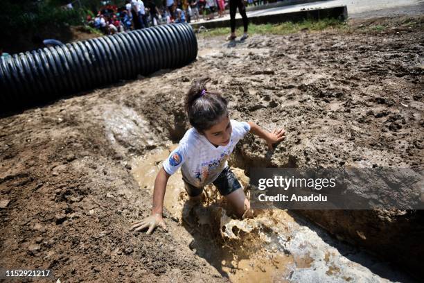 Kid competes in the obstacle racing track organized by using tin, tire, wood, bucket, slides, mud and net in Tarsus district of Mersin, Turkey on...