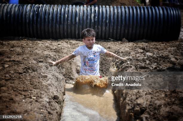Kid competes in the obstacle racing track organized by using tin, tire, wood, bucket, slides, mud and net in Tarsus district of Mersin, Turkey on...